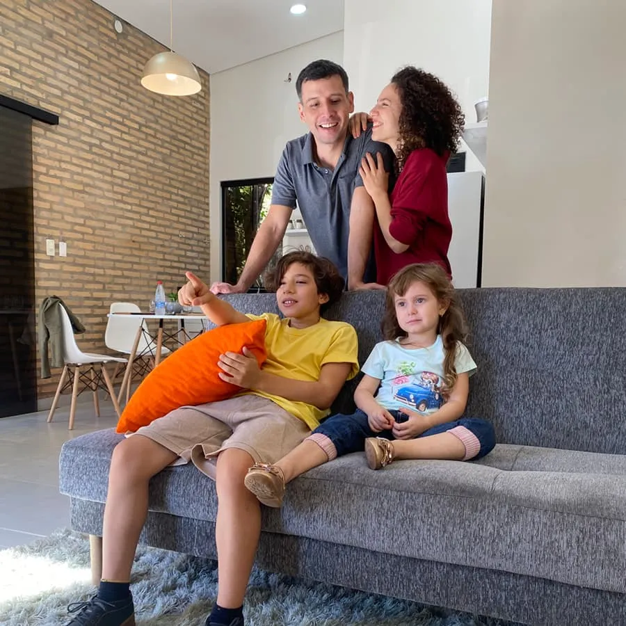 Familia viendo televison sobre el sofá en el living de casa más