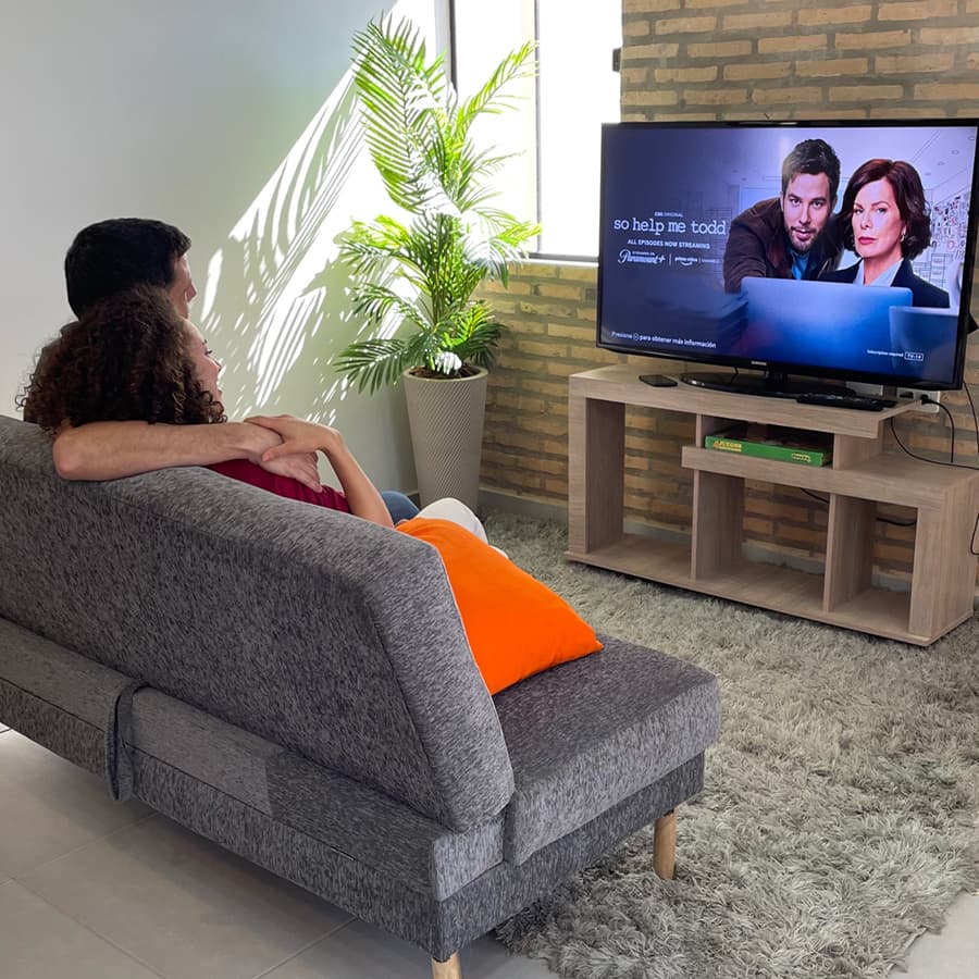 mamá y papá mirando televisión en el sofá del living de casa más