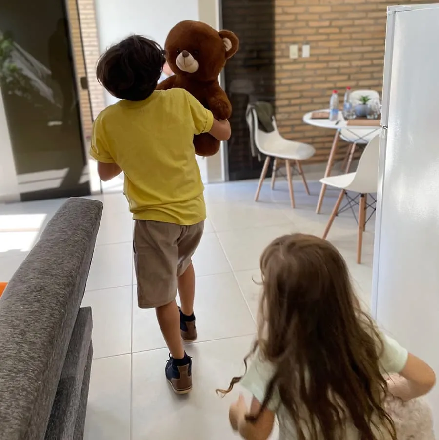 hijo corriendo con peluche de oso y hija corriendo detrás