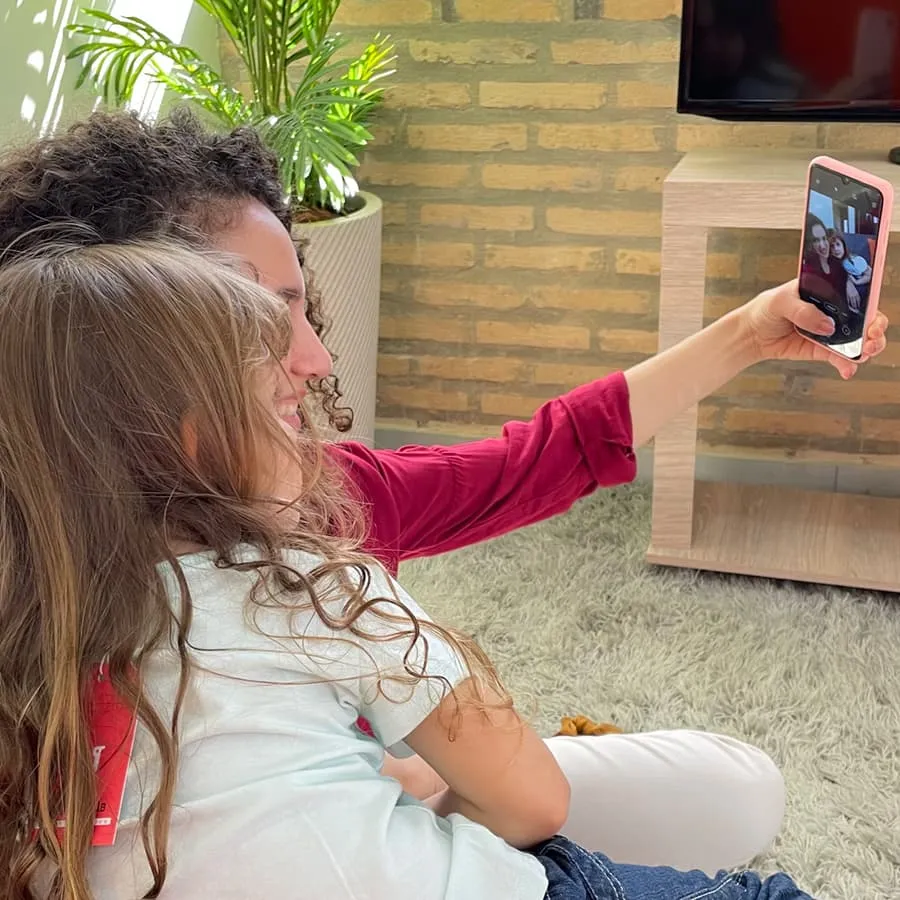 Mamá con su hija sacándose una selfie en la sala de casa más