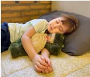 niño durmiendo feliz con su peluche en el dormitorio de casa más